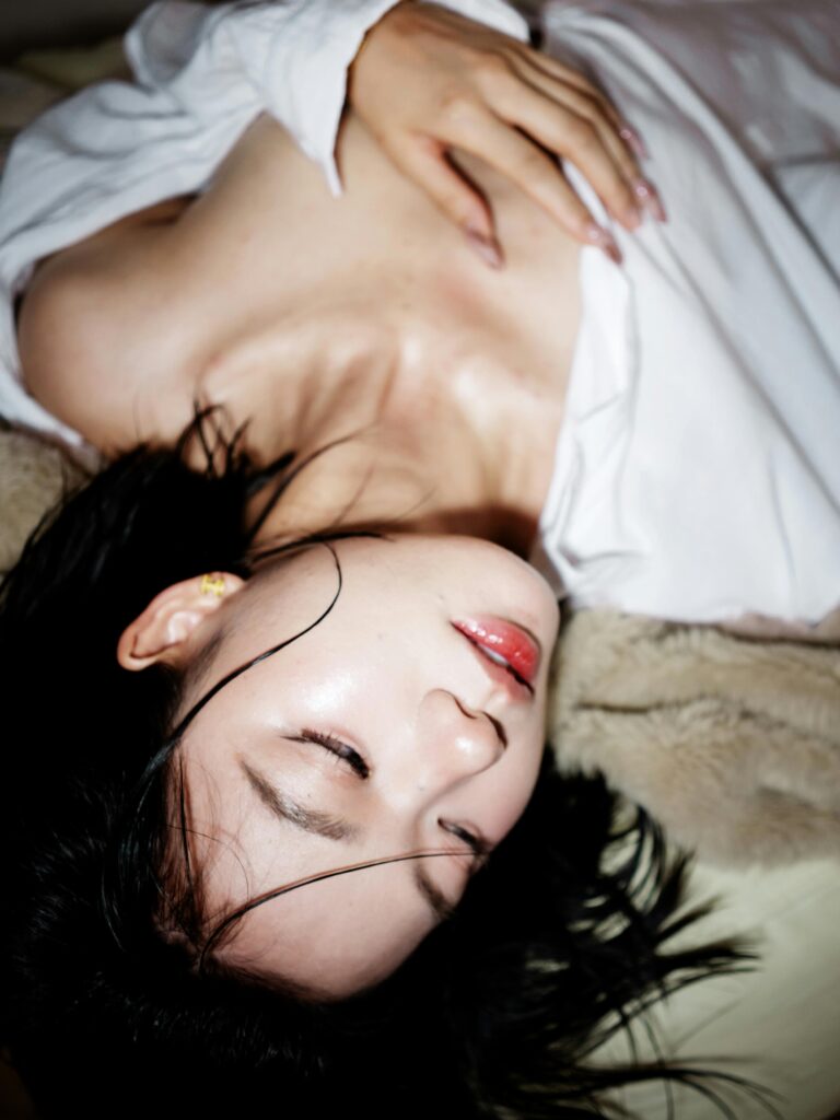 Artistic portrait of an East Asian woman lying down, showcasing elegance and tranquility.